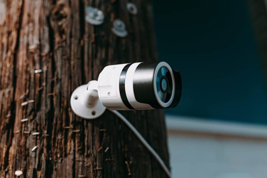 close up of a modern security camera mounted on a wooden post outdoors