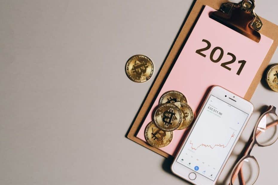 flat lay of bitcoins smartphone eyeglasses and clipboard with 2021 text symbolizing cryptocurren